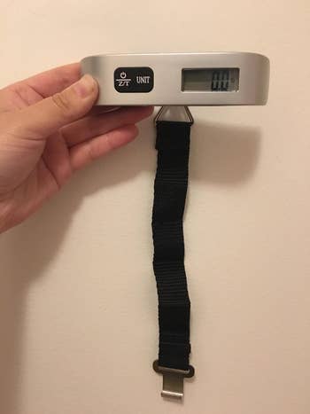 reviewer holding the luggage scale showing the attached strap