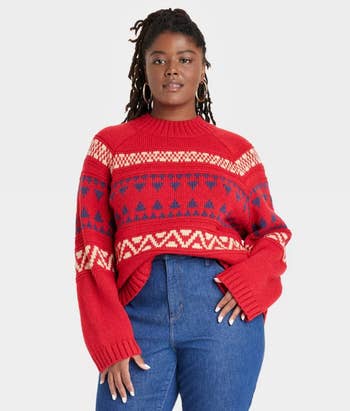 a model in a red colored sweater with a fair isle design on it in navy and cream