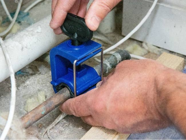 hands affixing clamp to a pipe