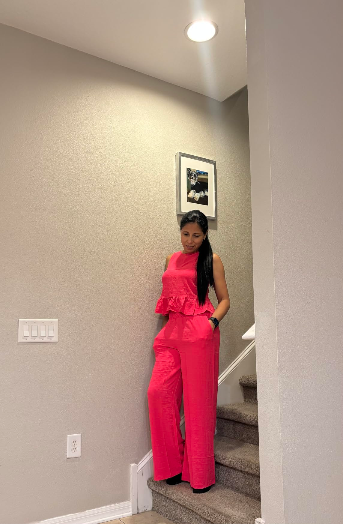 A idiosyncratic   stands connected  stairs, wearing a stylish, sleeveless jumpsuit with a peplum design, suitable for a chic, modern   look