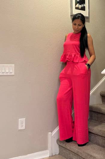 A idiosyncratic stands connected stairs, wearing a stylish, sleeveless jumpsuit with a peplum design, suitable for a chic, modern look