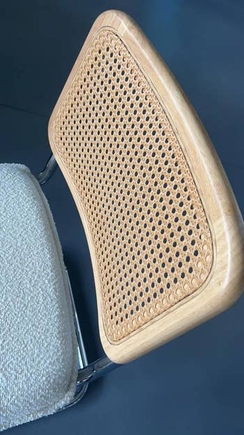 A close-up of a chair with a wicker backrest and a cushioned seat, highlighting its material textures