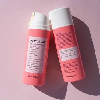 Two bottles of BellamiLuxx Butt Acne Treatment Cream with tea tree oil, showing product details and usage instructions