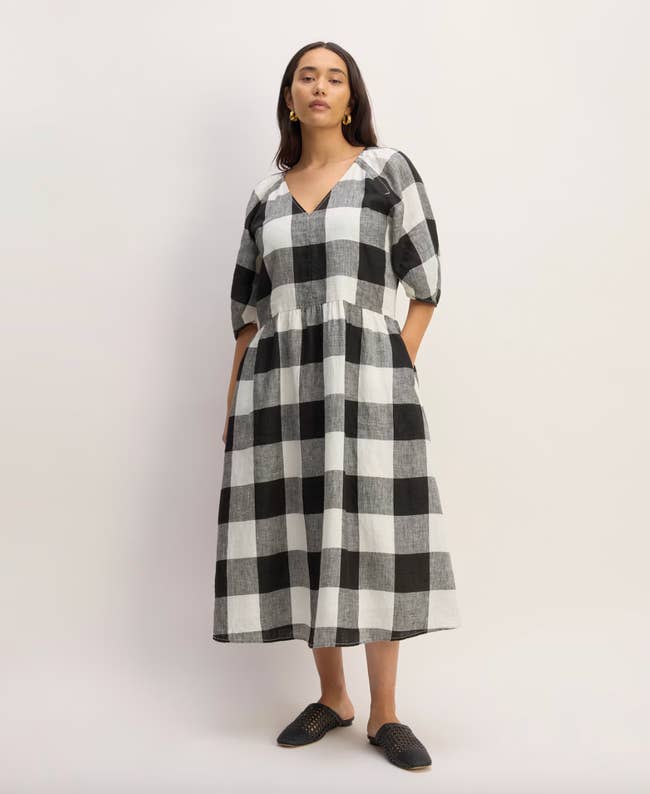 Model in a checkered midi dress and black flats