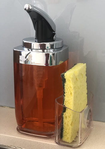 Reviewer image of clear soap dispenser with orange soap and yellow sponge