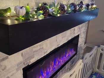 reviewer photo of garland styled on fireplace mantle with fairy lights