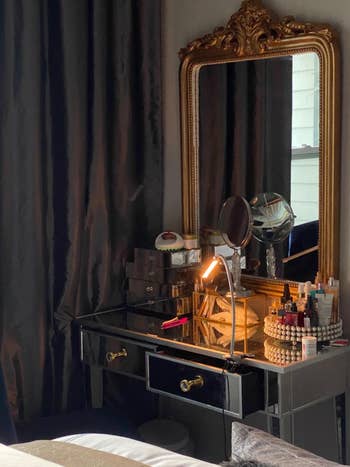 A vanity table with a mirror and assorted makeup and beauty products, reflecting a stylish interior