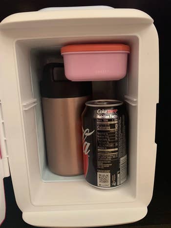 the inside of the mini fridge with a can of soda, soup thermos, and snack container