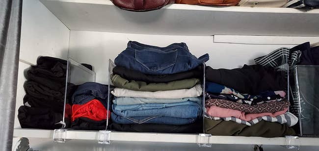 Clothes on a shelf with the dividers keeping them neatly organized 