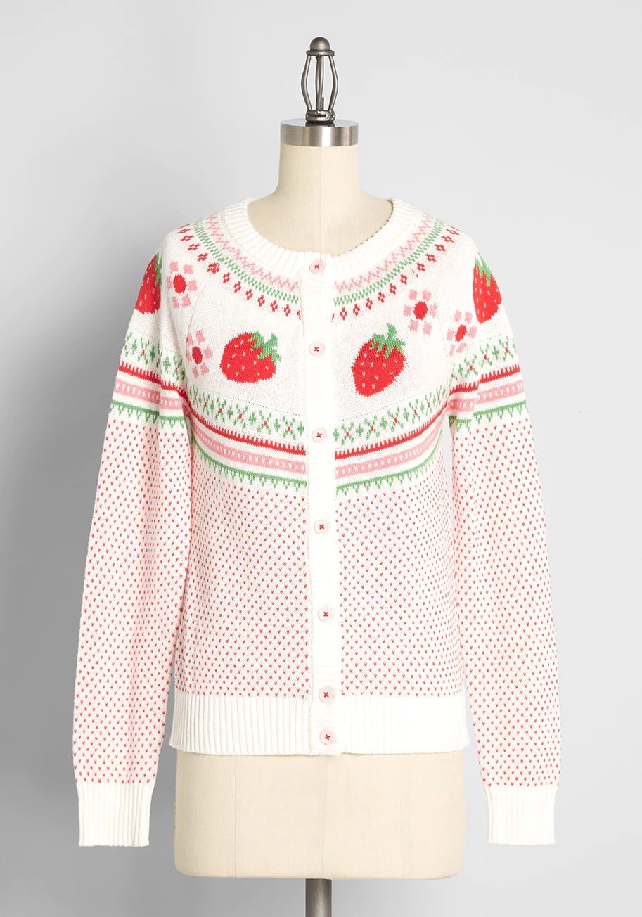 sweater with Fair Isle pattern at the yoke that features bright red strawberry motifs with pink and red flowers that are framed by red, green, and pink-hued zig-zags