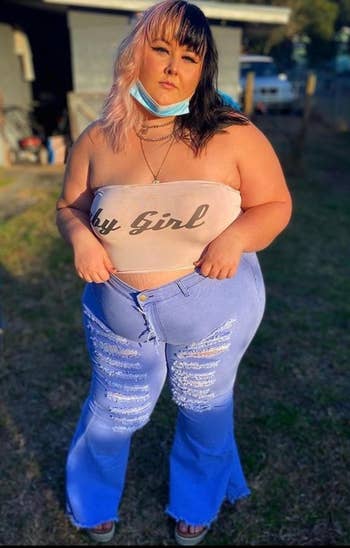 reviewer posing in light blue ripped bell bottom jeans