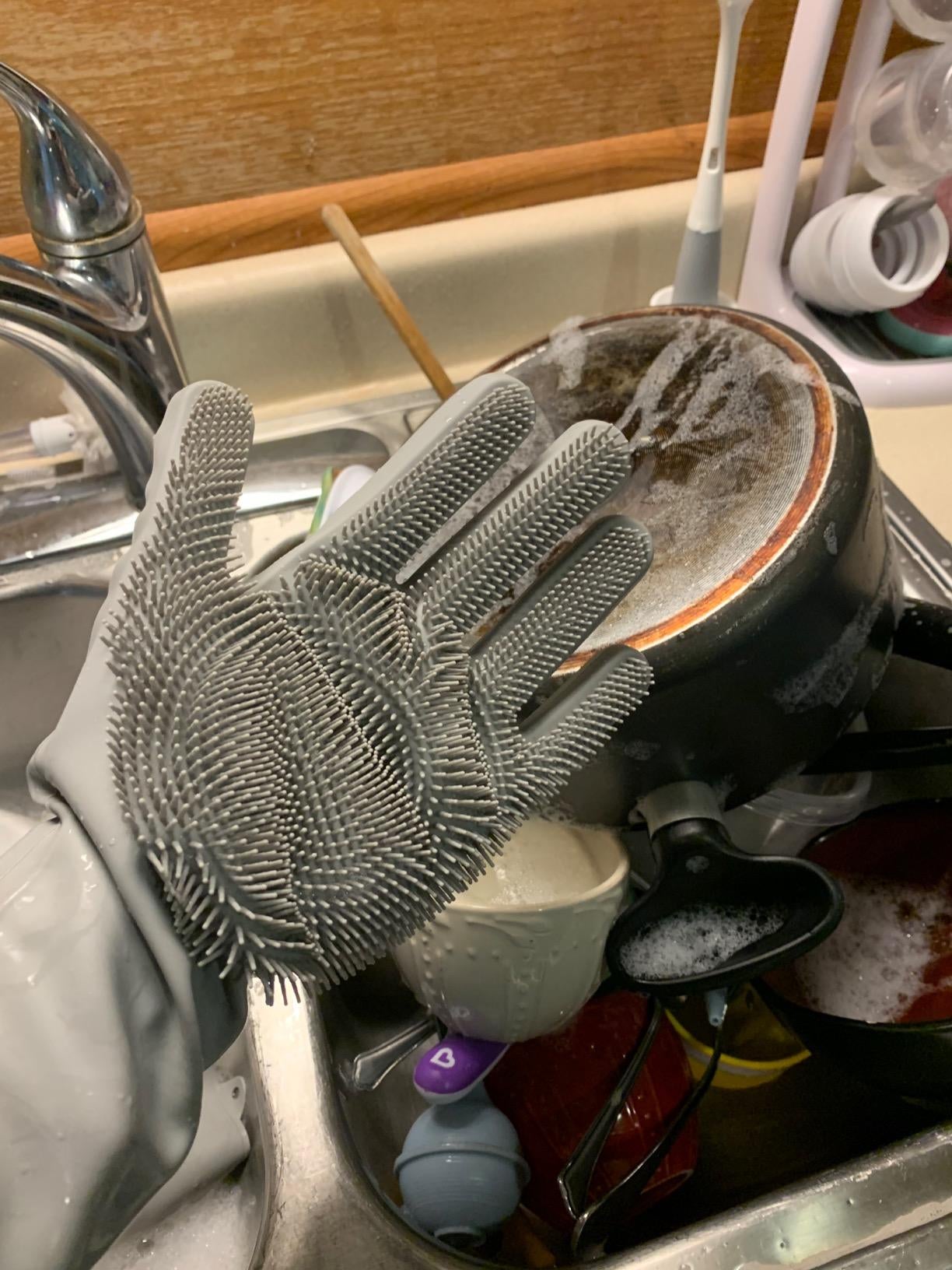 a reviewer wearing the grey gloves in front of a dish full of dirty dishes