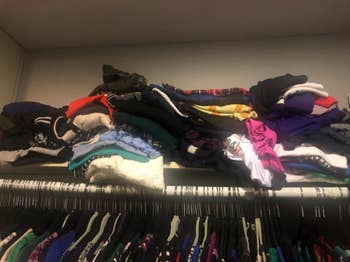 top shelf of closet with piles of shirts
