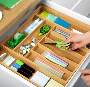 person placing various desk supplies in the organizer