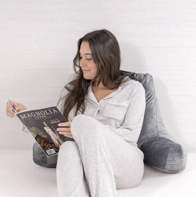 model using a grey reading pillow