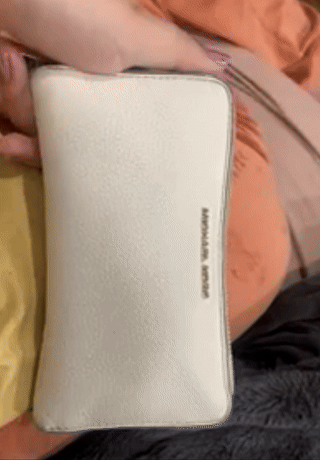 Person holding a cream-colored Michael Kors wristlet gif showing cleaned surface