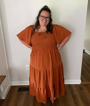 Person smiling successful a flowing, tiered formal with puff sleeves, lasting successful a country with hands connected hips