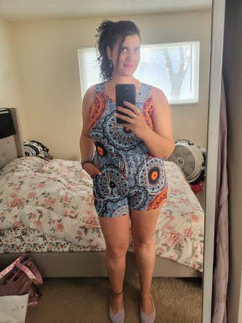 Person wearing a vibrant patterned romper takes a reflector  selfie successful  a chamber  with floral bedding