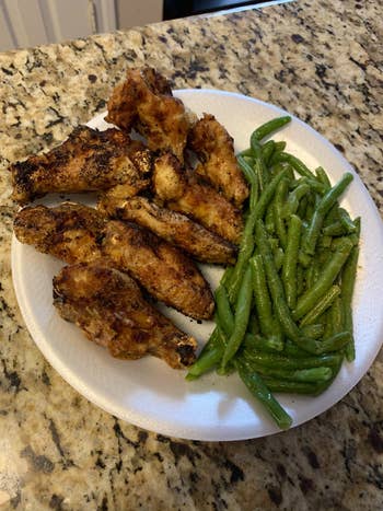 A sheet  of seasoned chickenhearted  wings paired with cooked greenish  beans, placed connected  a countertop