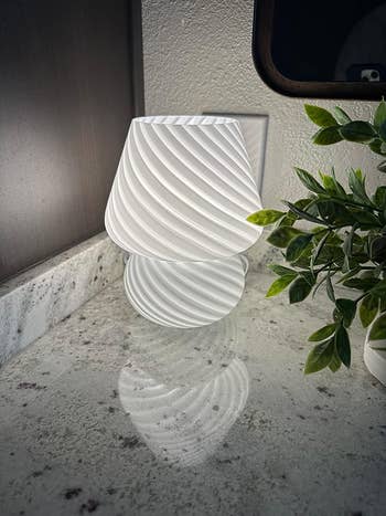reviewer's white striped mushroom lamp lit up 