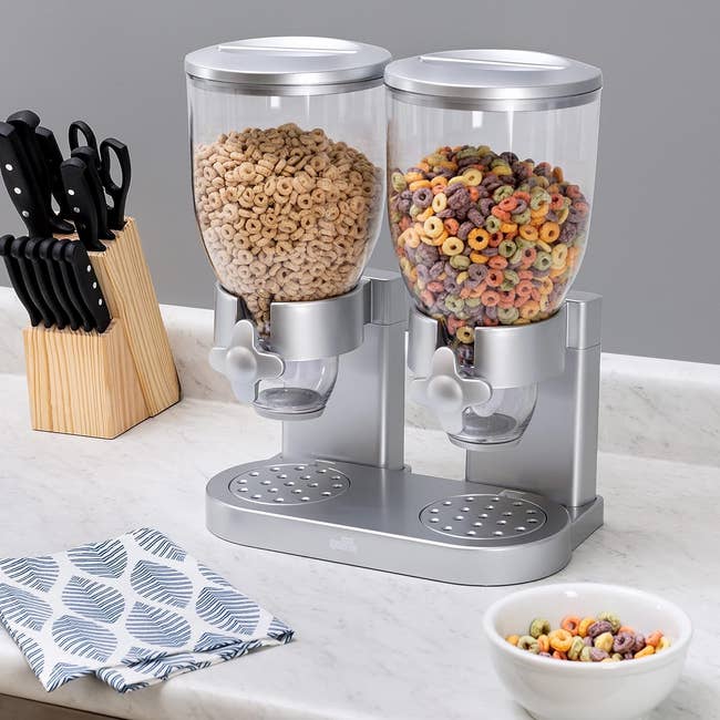 a double silver base cereal dispenser on a counter