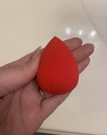 reviewer holding red makeup sponge