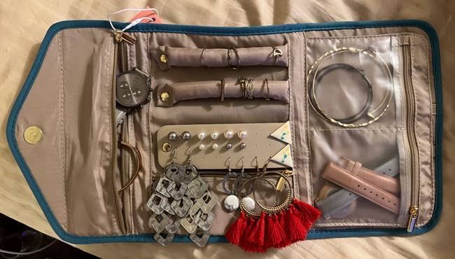 Jewelry organizer with various compartments holding earrings, bracelets, and watches