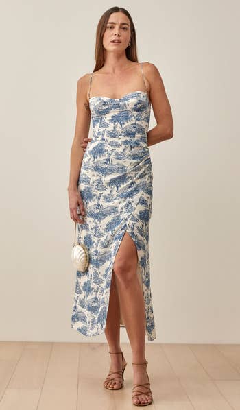 a model wearing a sleeveless midi dress in a blue a white print 