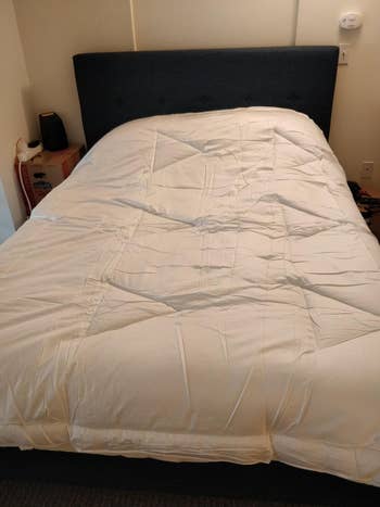 A neatly made furniture with a padded headboard and a achromatic comforter, acceptable successful a elemental bedroom