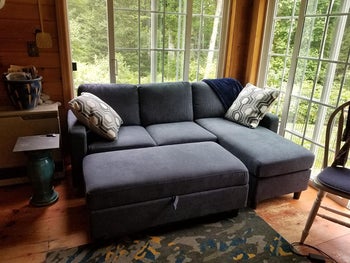 reviewer photo of the bluish gray sectional sofa with the ottoman pushed in to make it a sleeper