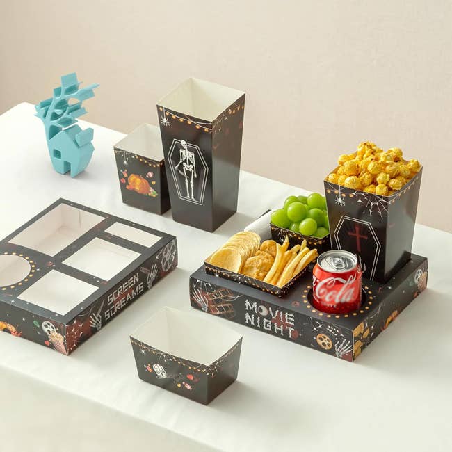 Snack trays with Halloween-themed designs clasp popcorn, soda, crackers, fries, and grapes, cleanable for a festive movie night