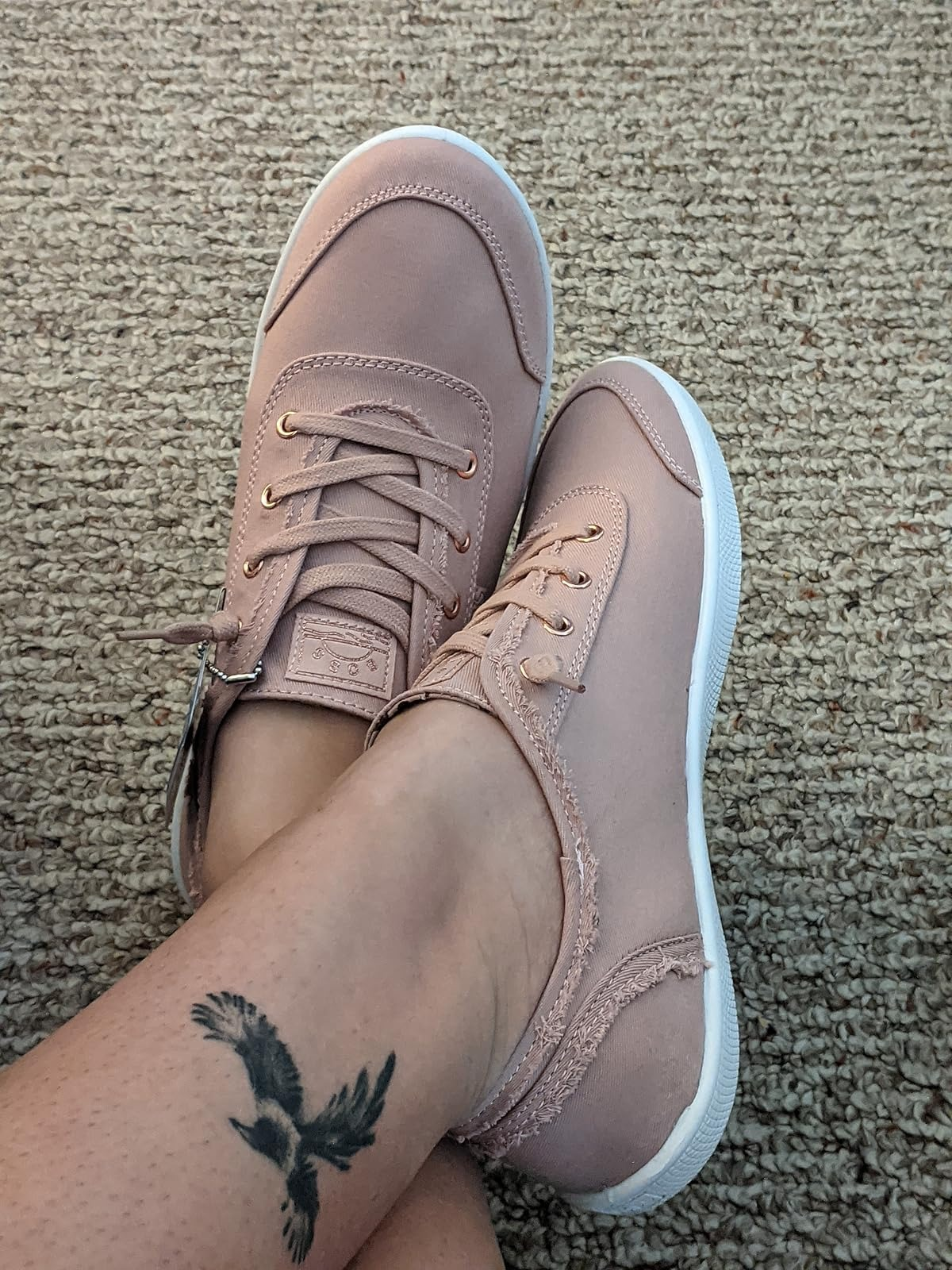 reviewer wearing pinkish  sneakers with achromatic  soles, showing a tattoo of a vertebrate  connected  their ankle