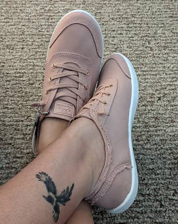 reviewer wearing pinkish sneakers with achromatic soles, showing a tattoo of a vertebrate connected their ankle
