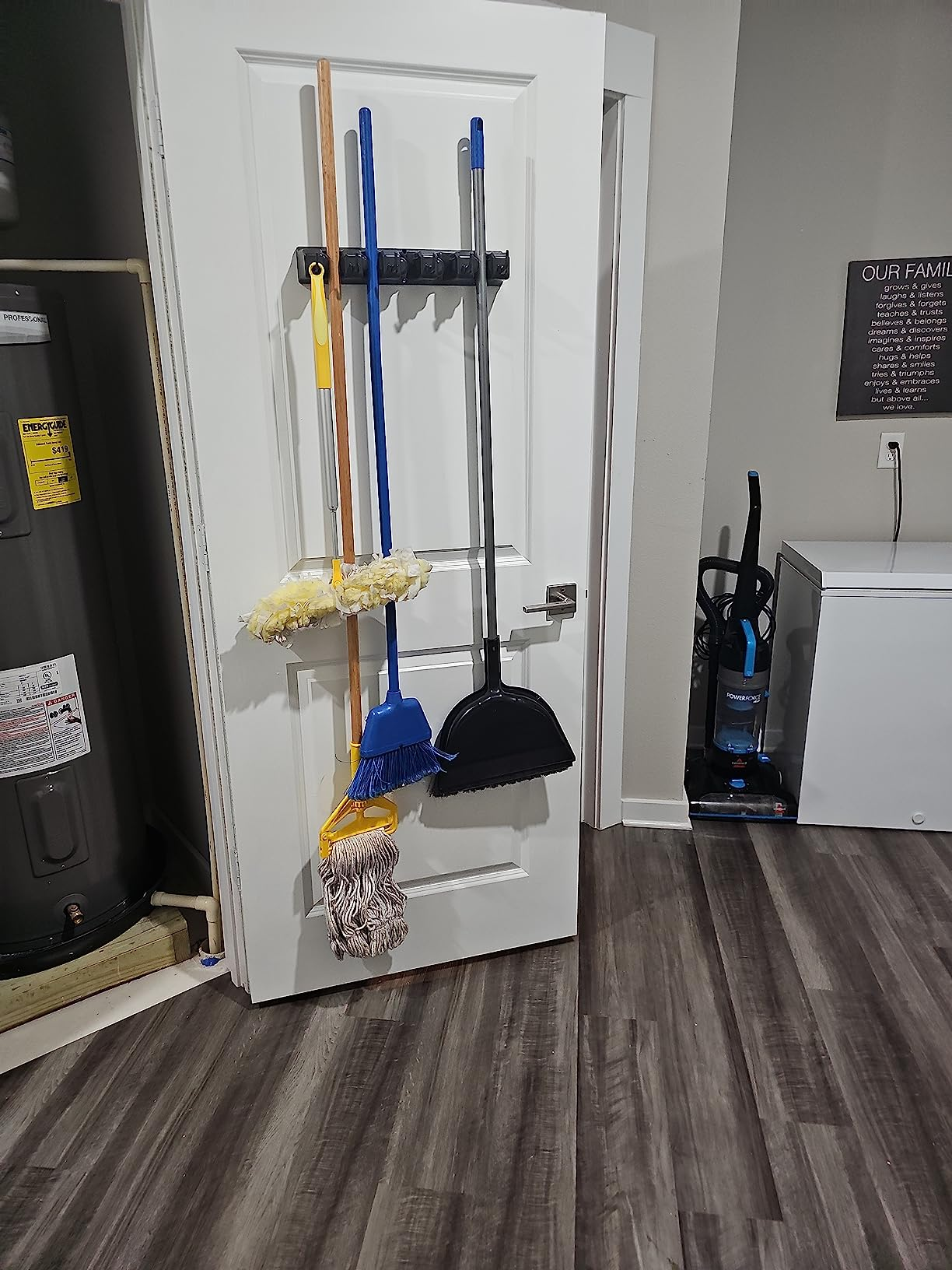 Cleaning supplies bent  connected  a doorway  rack successful  a inferior  country   with a mop, broom, and dustpan visible