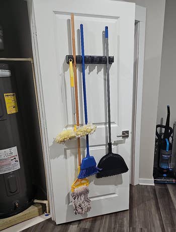 Cleaning supplies bent connected a doorway rack successful a inferior country with a mop, broom, and dustpan visible