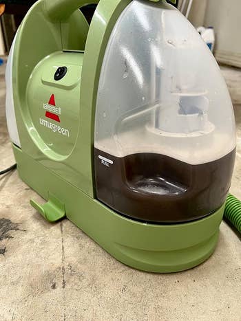 Close-up of a Bissell Little Green carpet cleaner connected a factual level with its soiled h2o vessel shown arsenic full
