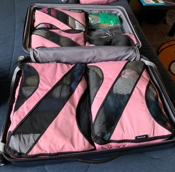 reviewer photo of the pink and mesh packing cubes in a suitcase