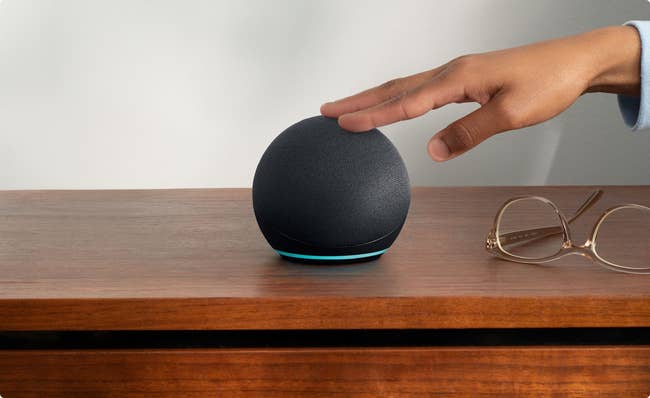 a model's hand taps the echo dot