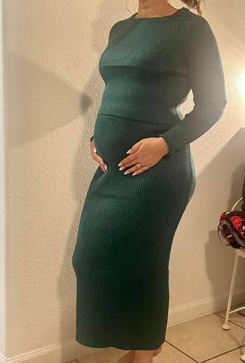 A large   reviewer successful  a acheronian  greenish  form-fitting, long-sleeved formal  cradles her belly.