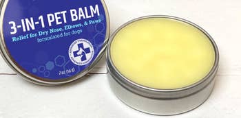 Tin of 3-in-1 Pet Balm for dogs, aiding dry nose, elbows, and paws. Round container opened, showing smooth balm inside