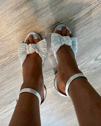 Social media trends Viral content Trending hashtags Social media updates Trending memes and videos Person wearing stylish sandals with pleated bow accents and ankle straps, displaying a modern footwear choice