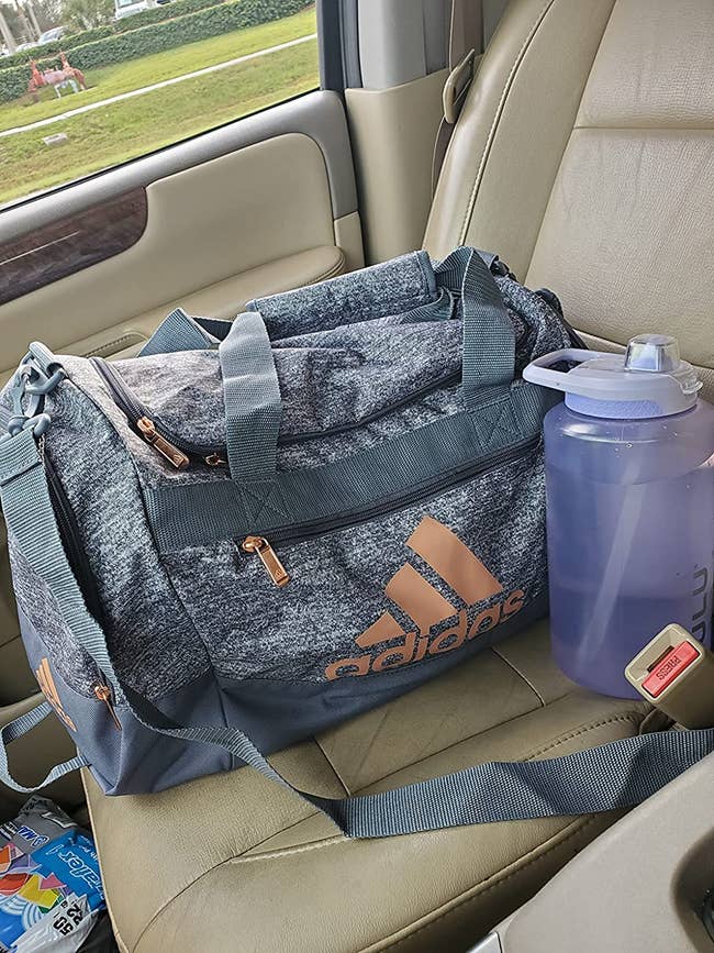 reviewer's grey Adidas duffle bag in the front seat of a car