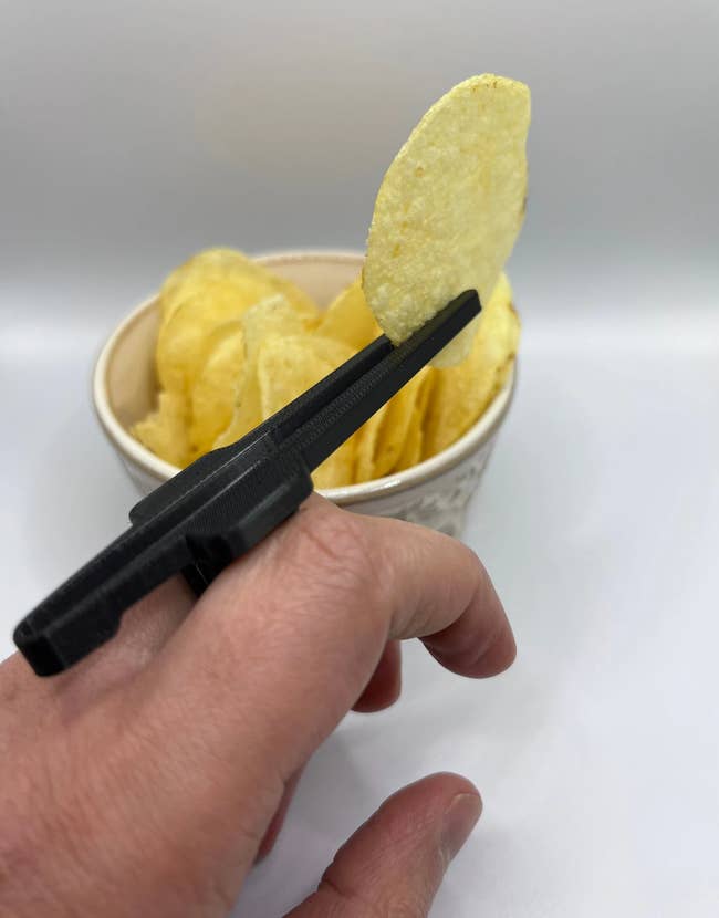A person using the chopsticks to pick up a chip