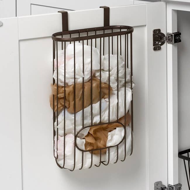 A metallic  container  dispenser attached to a furniture  door, holding aggregate  integrative  market  bags