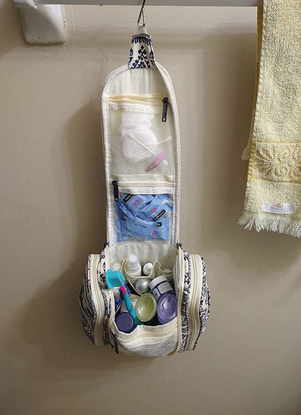 Blue and white patterned toiletry bag full of stuff hanging from the towel bar