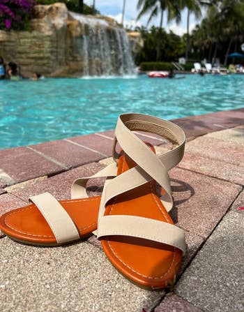 reviewer's beige sandals in front of a pool