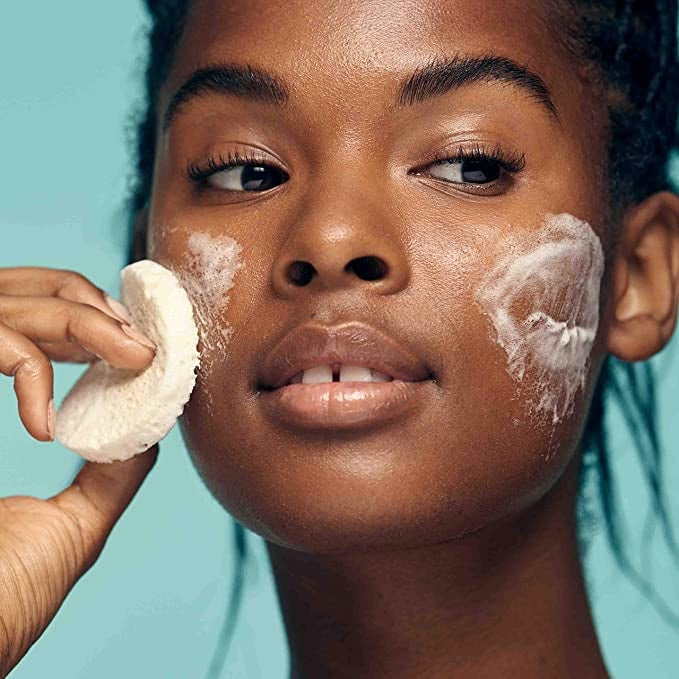 model rubbing cleansing bar across cheeks