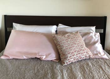 Reviewer image of pink and white silk pillows on a bed
