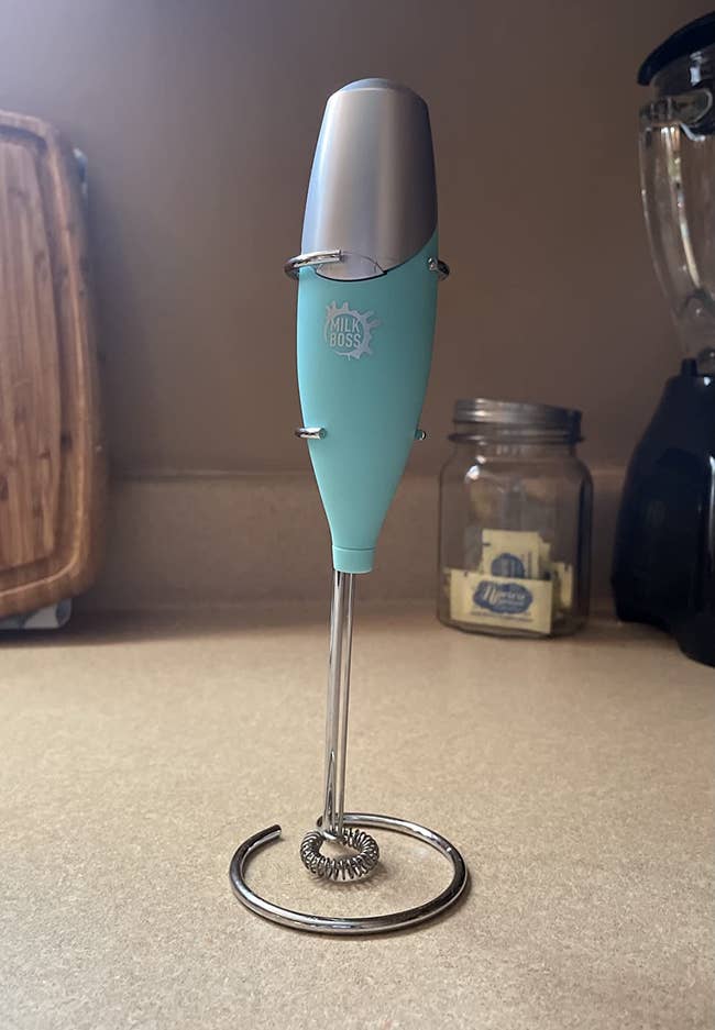 Reviewer image of teal milk frother with silver whisk on top of counter