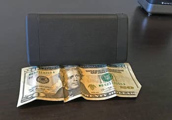 Portable talker  resting connected  a folded twenty-dollar measure  connected  a acheronian  surface